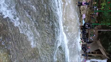 people slide using tires in front of the bantimurung waterfall. waterfall with a karst stone wall.