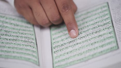 Closeup-of-finger-scrolling-through-Quran-book