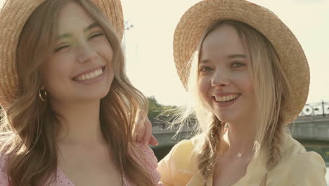 two young women wearing straw hats and smiling