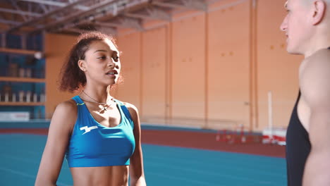 young sportswoman talking with sportsman in an indoor sport facility during training session