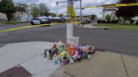 Circular-view-of-a-crime-scene-fenced-by-police-with-tape-where-people-have-placed-flowers-and-candles