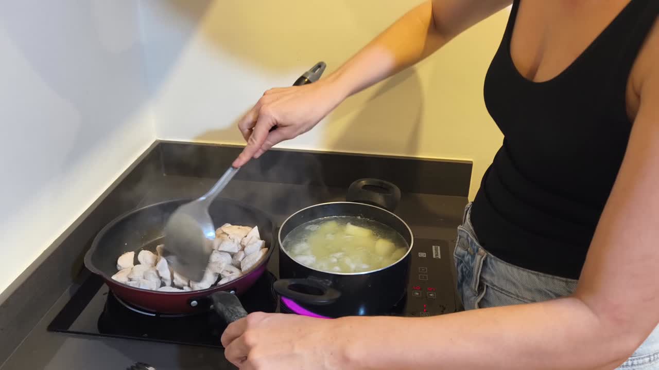 Woman cooking chicken and potatoes on stovetop
