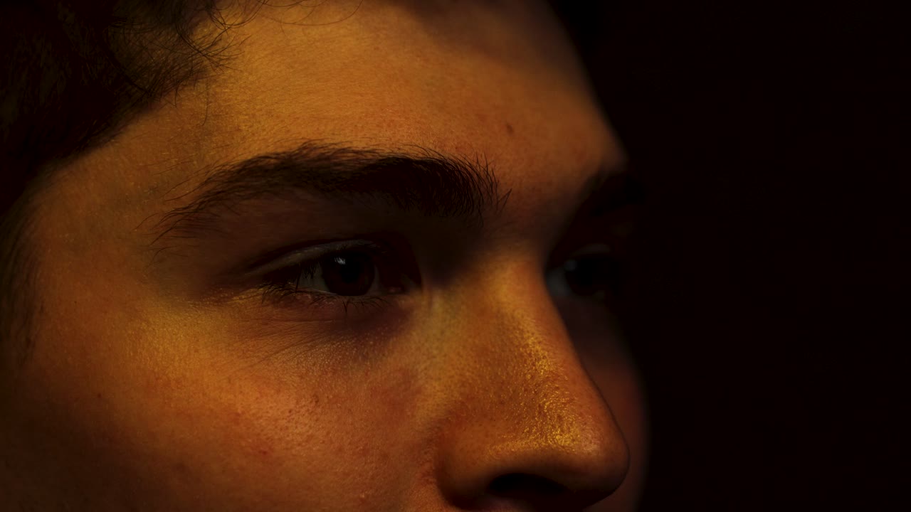 hombre sonríe y ríe mientras la cara está iluminada viendo algo en una habitación oscura