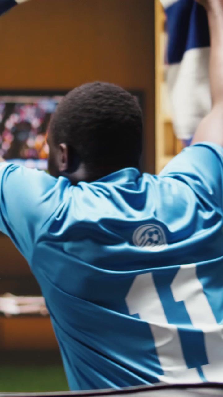 Video verticale: Primo piano di tifosi di calcio che giocano con un pallone sul divano di casa.