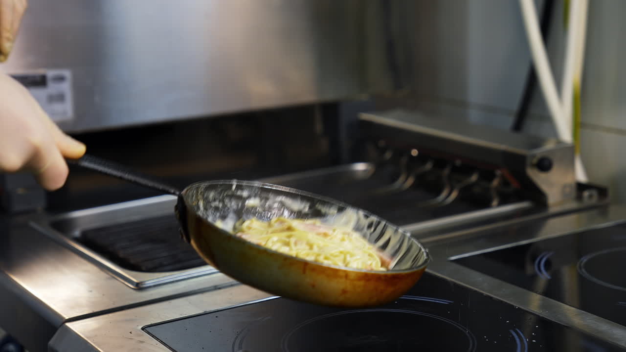 Spaghetti with bacon, herb and egg on frying pan. Chef turns carbonara on frying pan. Tasty dishes.