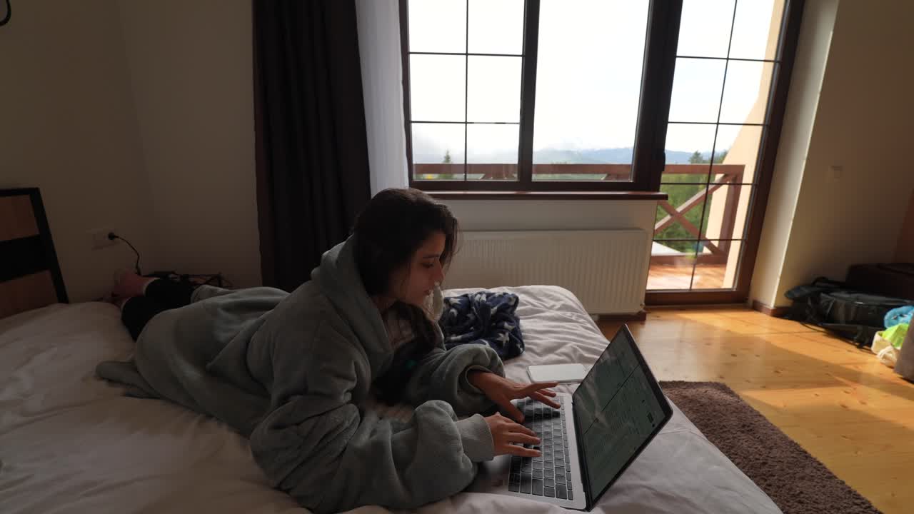 Woman Working on Laptop in a Cozy Bedroom with Mountain View