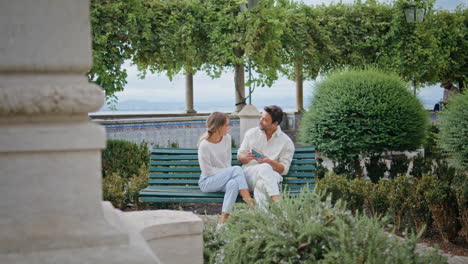 cheerful couple sitting bench laughing at urban park. lovely pair kissing date