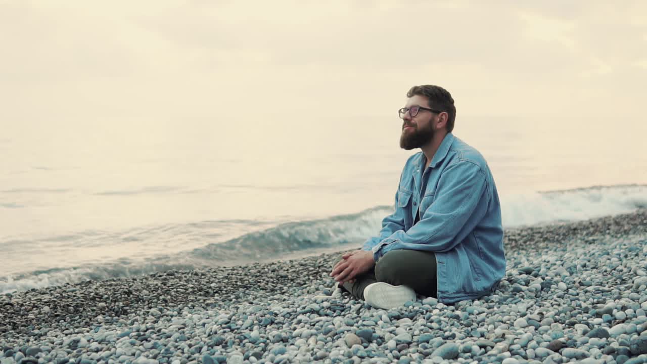 hombre meditando en la playa al amanecer o al atardecer