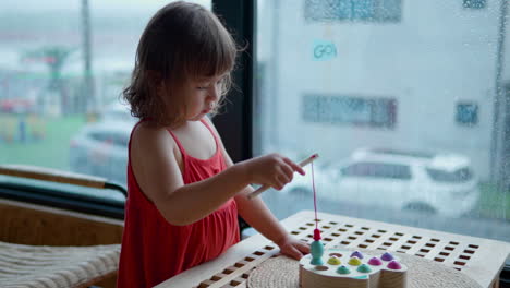 Niña-Pequeña-Jugando-Con-Un-Juego-De-Pesca-Magnético-De-Madera,-Atrapando-Peces-Con-Caña,-Niño-Aprendiendo-Habilidades-Motoras-Finas-Y-Coordinación-Mano-ojo