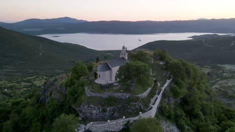 hilltop church against beautiful lake at sunset, montenegro