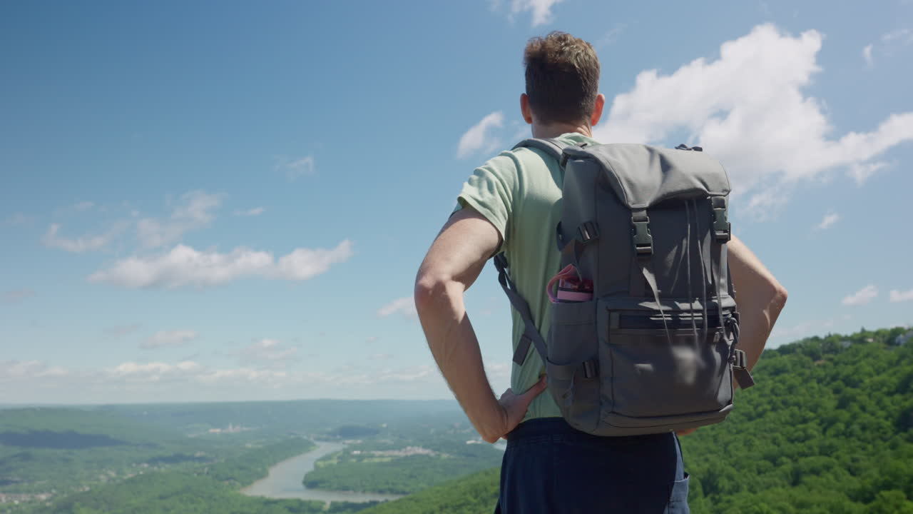 joven de pie en la cima de una montaña y mirando la hermosa vista de la naturaleza desde lo alto