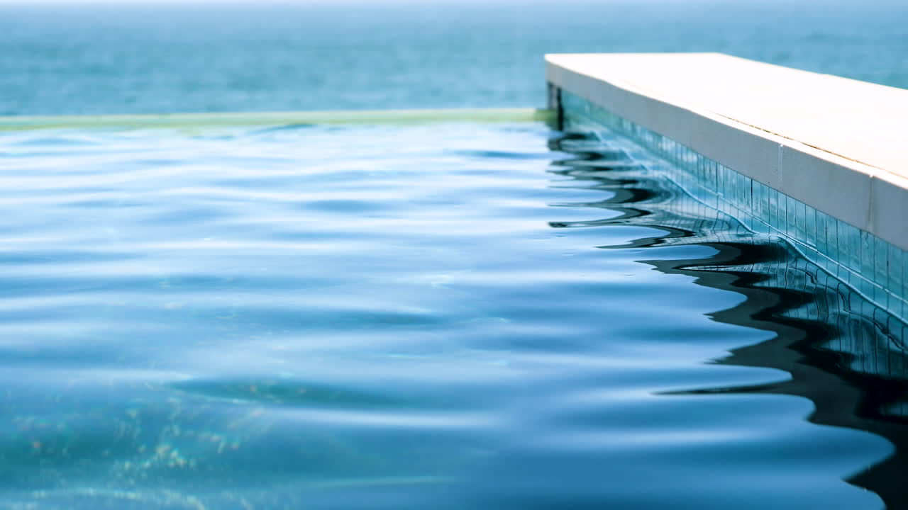 Lage statische opname vanaf de rand van een blauw zwembad met bewegend oppervlakte water