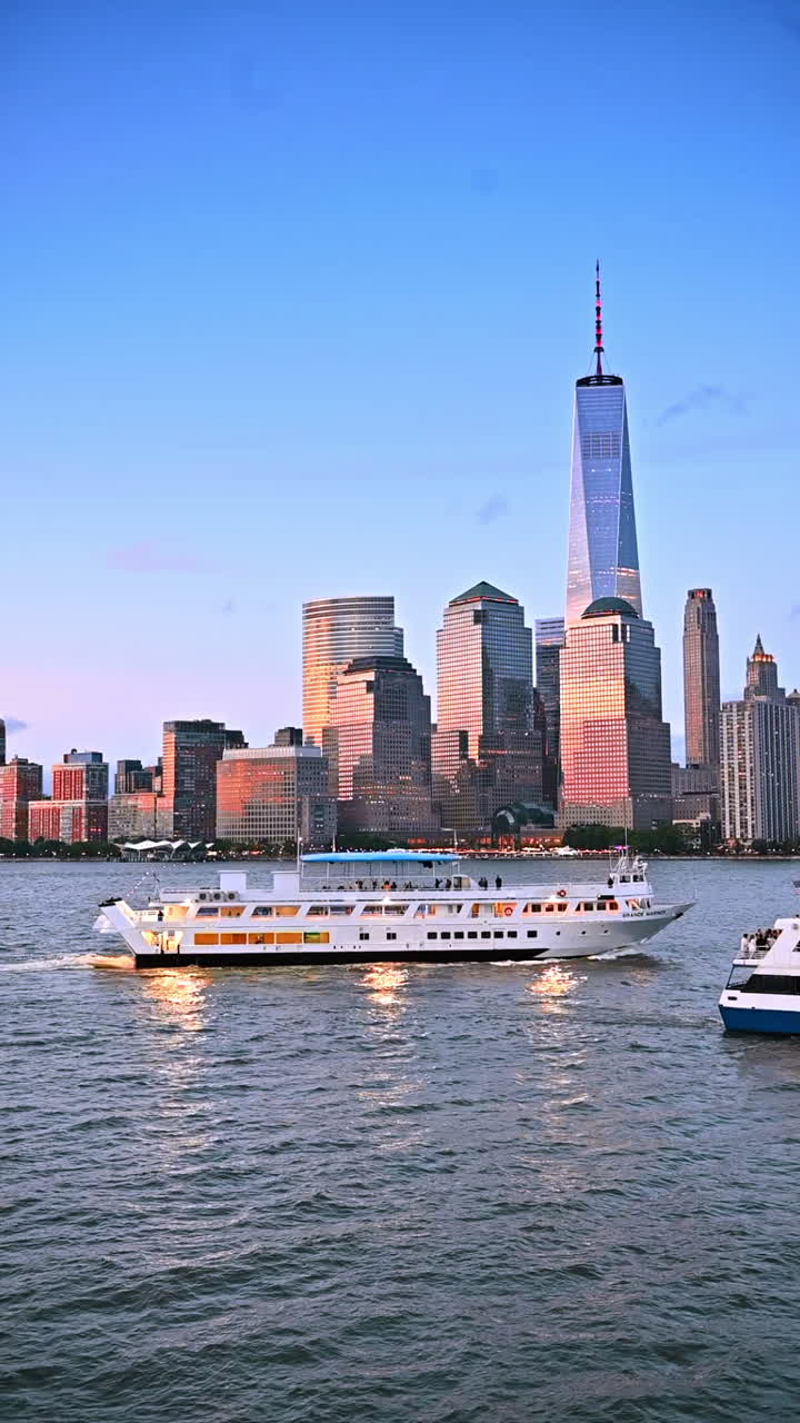 New York, USA, 8 luglio 2025: moderna imbarcazione a più ponti naviga nel paesaggio fluviale al tramonto. Le facciate in vetro degli edifici di Manhattan riflettono il sole che tramonta sullo sfondo. Video verticale