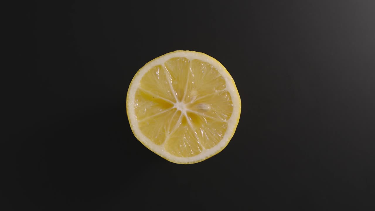 la mitad del limón gira sobre una superficie negra. vista superior. detener el movimiento