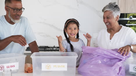 Biracial-family-sorts-recycling-in-a-bright-kitchen;-the-child-is-excited