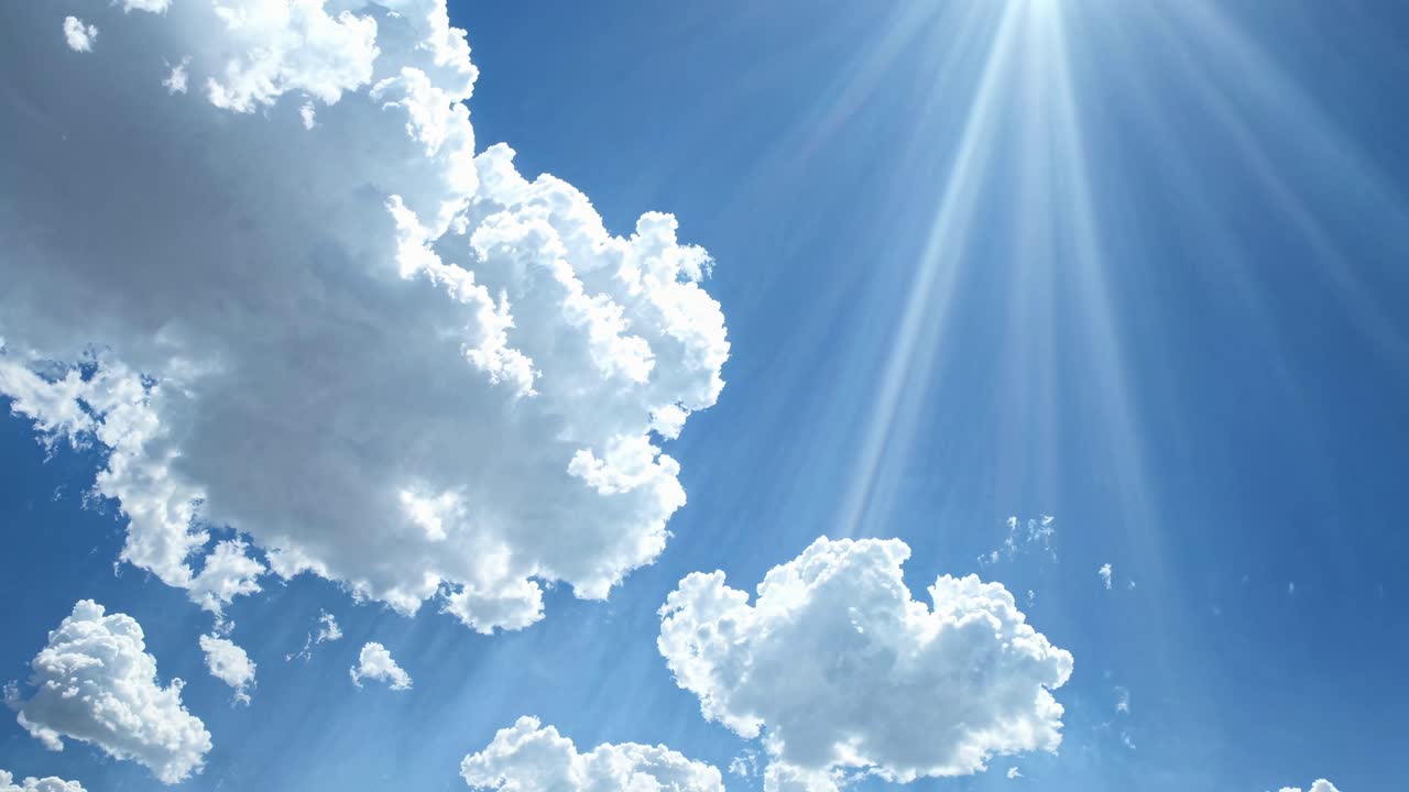 Aerial video view of bright sun rays piercing through fluffy clouds in a vibrant blue sky