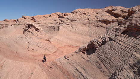 Lonely-Woman-Walking-on-Sandstone-Hills-on-Hot-Sunny-Day,-Arizona-USA