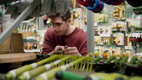 exploring gardening equipment at a specialized store with a young man in brown sweater and glasses