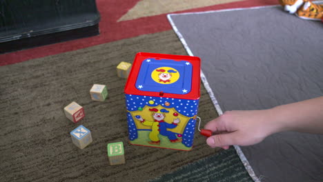 a woman's hand winding a jack-in-the-box toy until it pops up