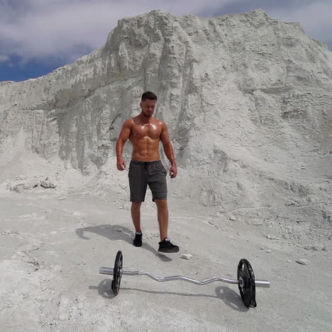 strong man with athletic body comes to barbell on beautiful white mountain. slow motion. strength and endurance training for wrestlers.