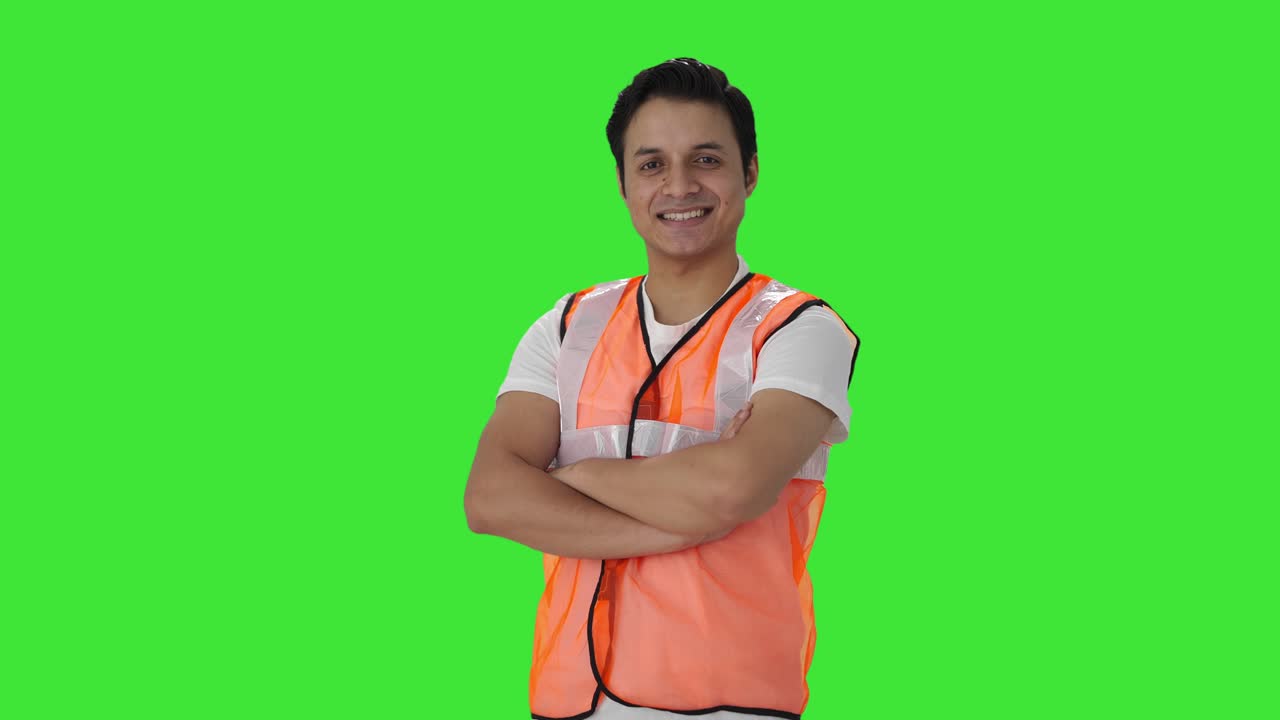 retrato de un feliz trabajador del aeropuerto indio de pie con las manos cruzadas pantalla verde