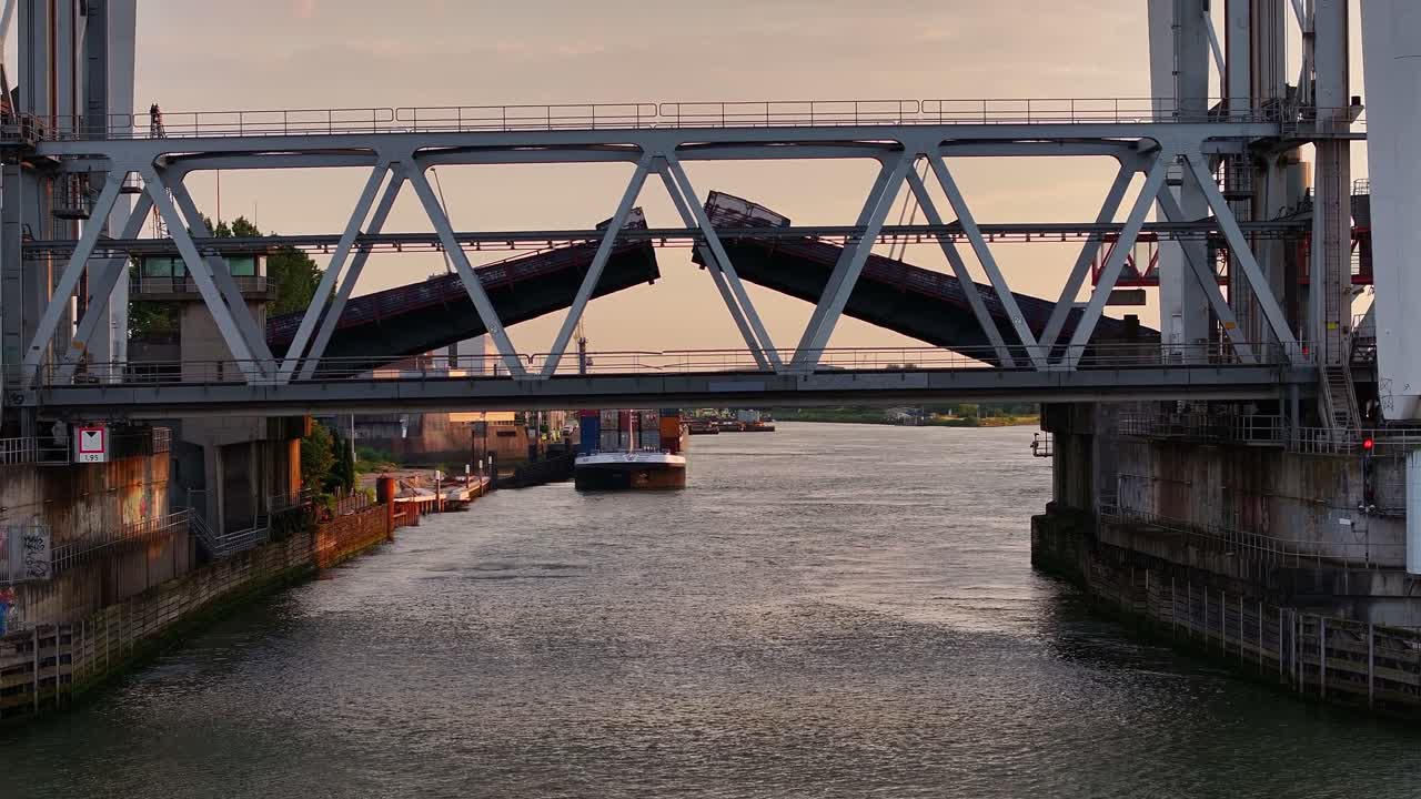 Cargo ship seen through bridge being opened over Dutch river, aerial