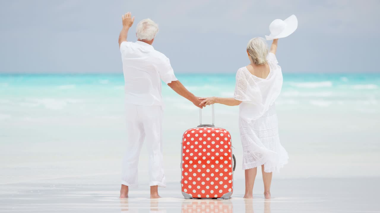 una pareja de ancianos jubilada en la playa con equipaje de viaje