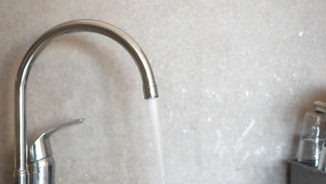 close up of a chrome kitchen faucet with water running