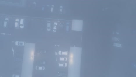 bird's eye view over car parking covered in fog in szczecin poland - drone shot