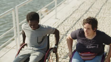 Two-happy-friends-with-disability-wheeling-down-on-quayside