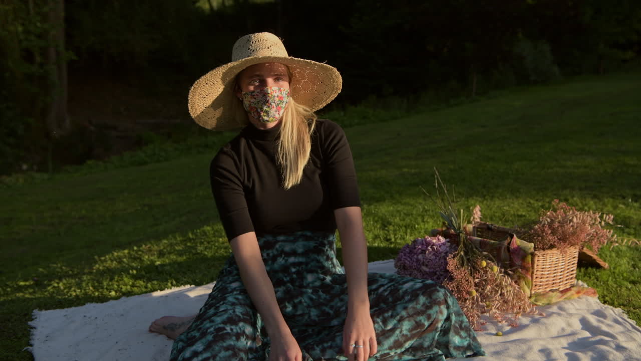 Stylish Woman Wearing Face Mask Sitting on Picnic Blanket, Lockdown