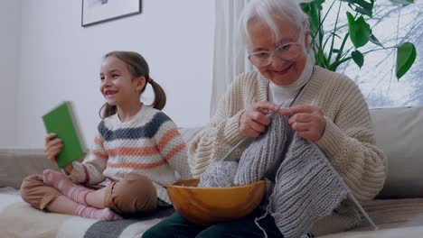 proud granny sitting on a couch with her granddaughter.