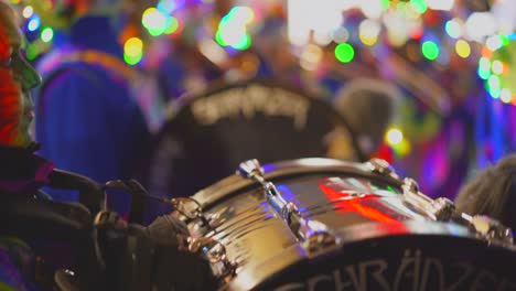 disguised person with make up mask playing bass drum on party event in city at night