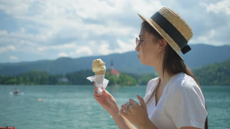 una mujer comiendo helado junto a un lago.