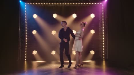 professional ballroom dancers performing on a stage with dynamic lighting