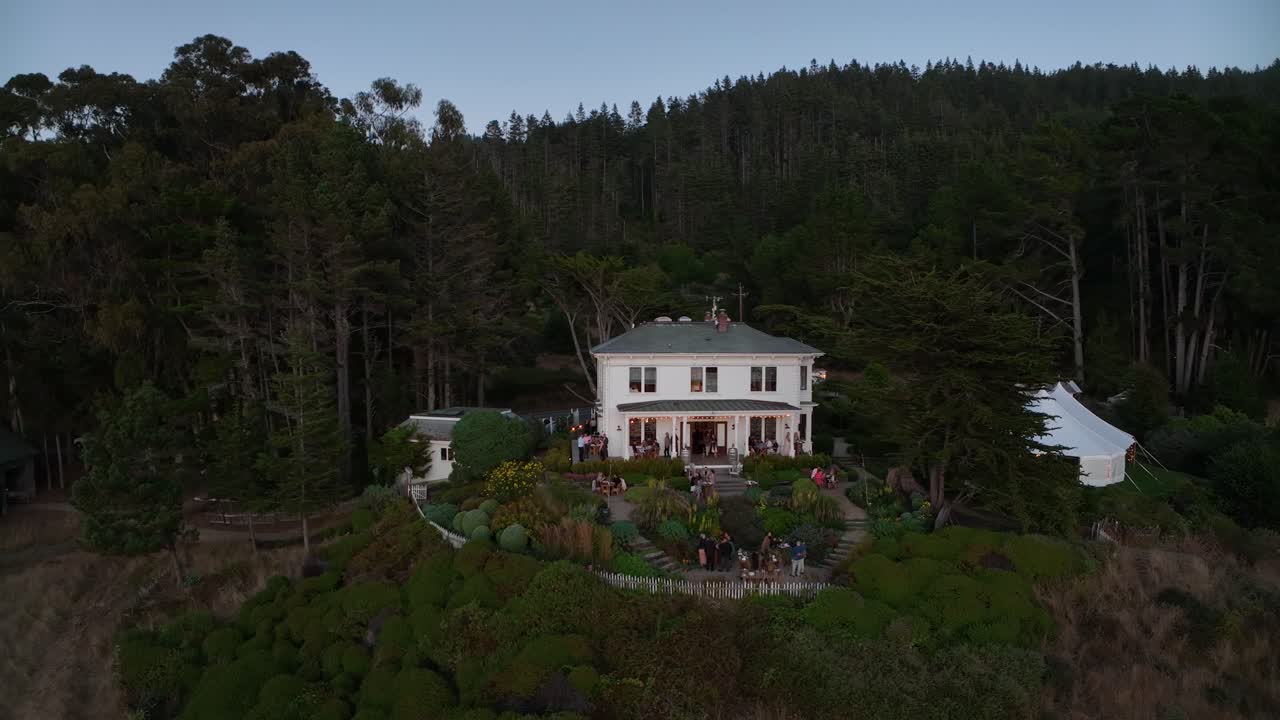 저녁에 개인 결혼식 장소의 넓은 드론 샷, 사람들이 술을 마시며 밖에서 어울립니다.