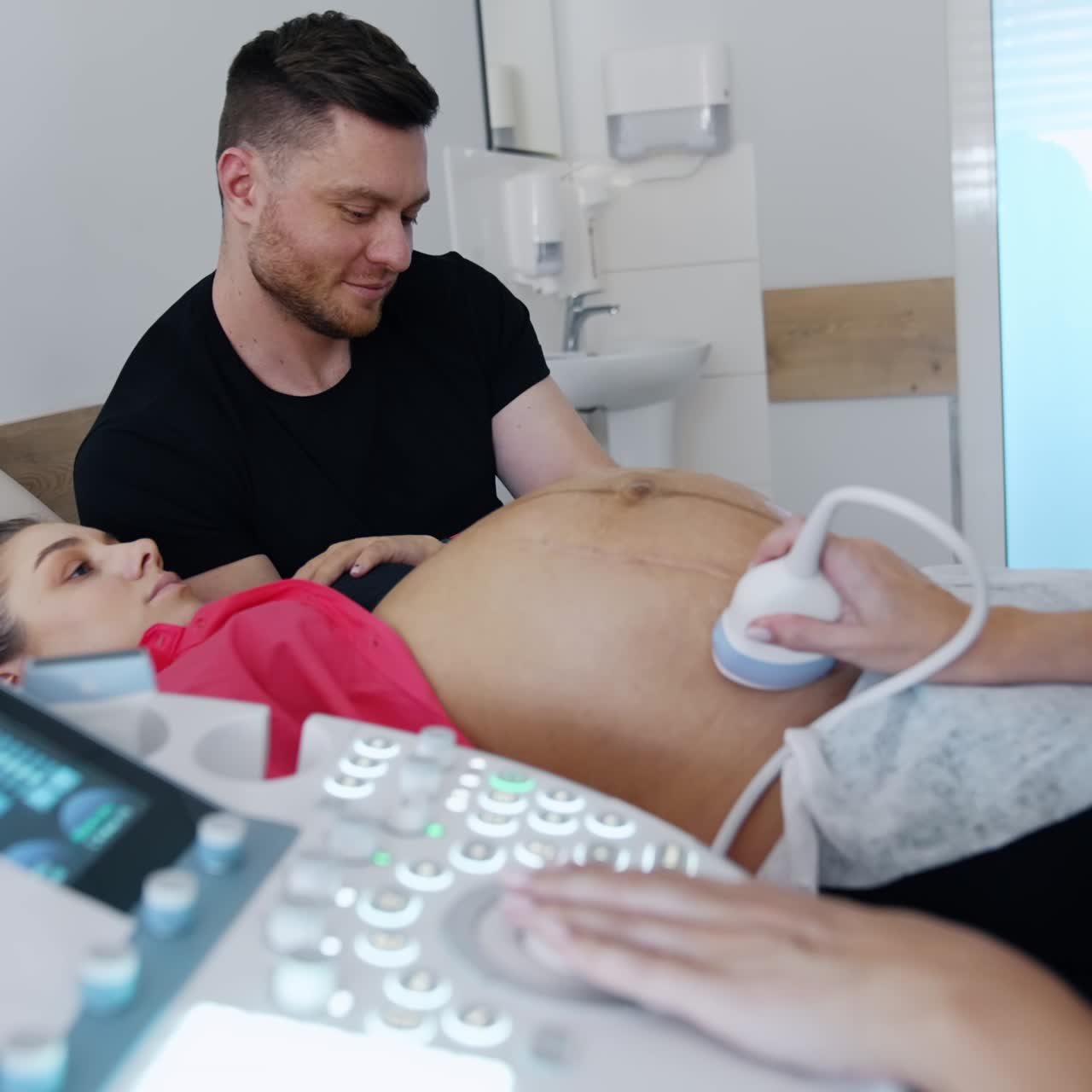 Caucasian couple is in the doctor's cabinet. Pregnant woman has ultrasound check up