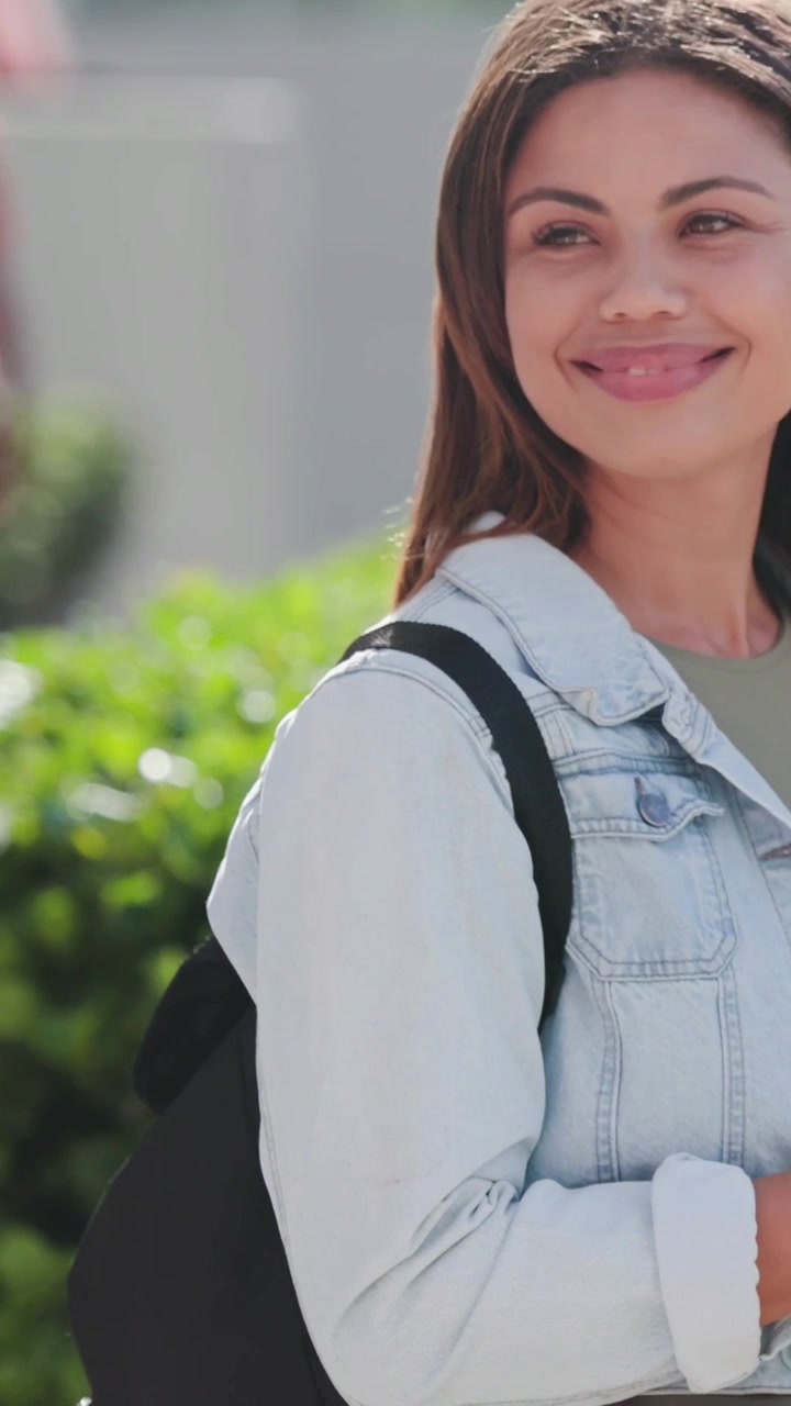 Video verticale: Una donna in denim alza lo sguardo e poi tocca il telefono, controllando l'ora sull'orologio mentre è sul marciapiede.