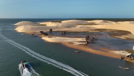 indigenous native people wooden huts near parnaiba river tributary, sand dune landscape, drone