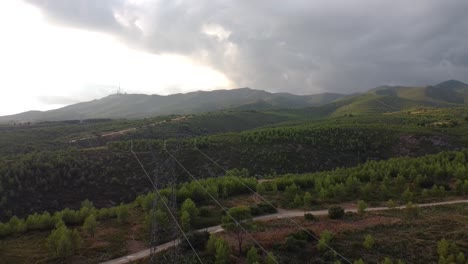 Toma-De-Drones-De-Un-Paisaje-Montañoso-árido-Cubierto-De-Couds-Con-Una-Torre-Eléctrica-Y-Cables