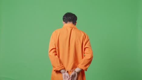 back view of asian male prisoner in handcuffs walking on the green screen background