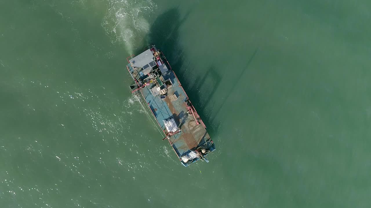 antena de arriba hacia abajo de un barco de trabajo de mejillones de mariscos con una cinta transportadora moviéndose en el tranquilo mar turbio