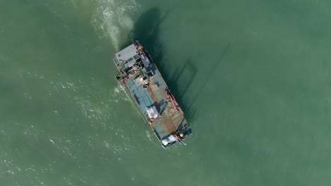antena de arriba hacia abajo de un barco de trabajo de mejillones de mariscos con una cinta transportadora moviéndose en el tranquilo mar turbio