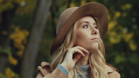 Close-up-view-Caucasian-young-blonde-woman-in-a-hat-thinking-about-something-in-the-park-in-autumn