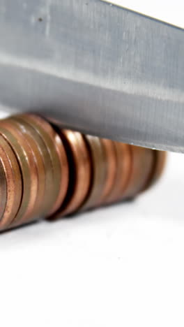 knife cutting row of coins