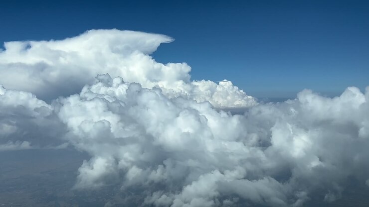 Immersive pilot POV flying through a blue sky with some fluffy clouds and a massive storm cloud ahead