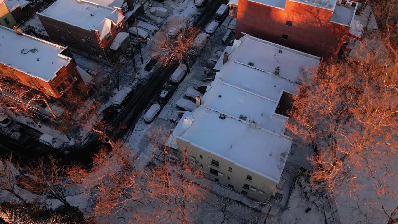 An aerial shot of houses covered in snow after a snowy day, with the camera pointing downward and pushing forward.