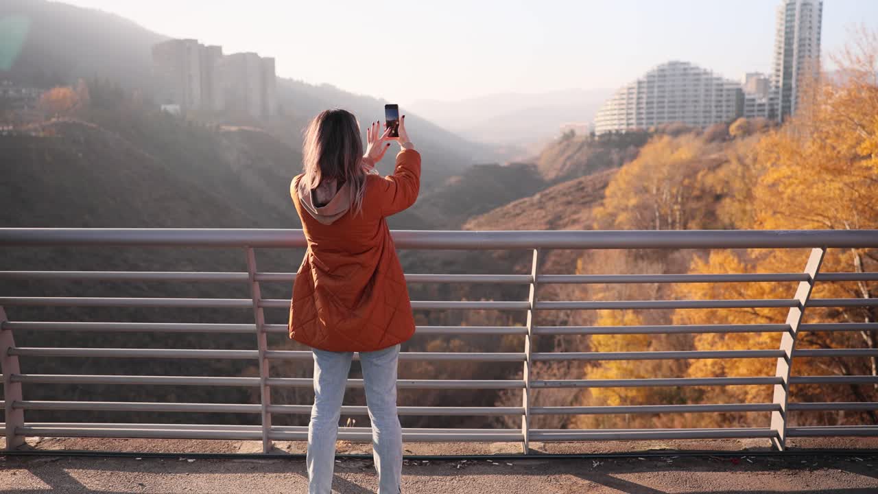 Woman taking pictures of a cityscape in autumn