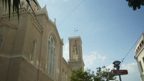 Church-spire-and-Greek-flag-by-the-Acropolis-sign-under-clear-skies