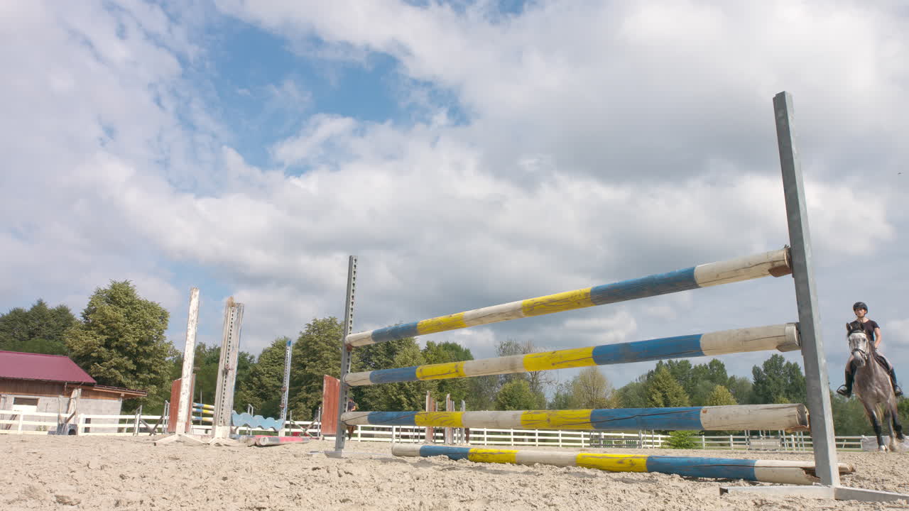 chica montando un caballo y saltando obstáculos en la escuela de equitación, de mano